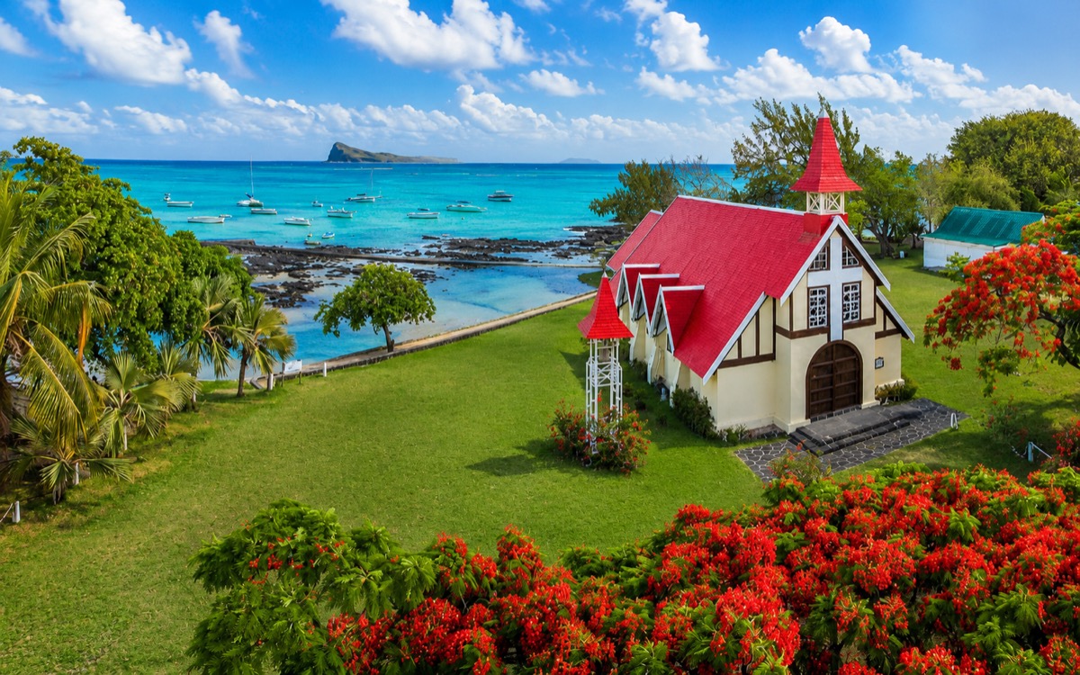 The iconic red-roofed Notre-Dame Auxiliatrice church at Cap Malheureux, with Coin de Mire island beyond, on the northern tip of Mauritius