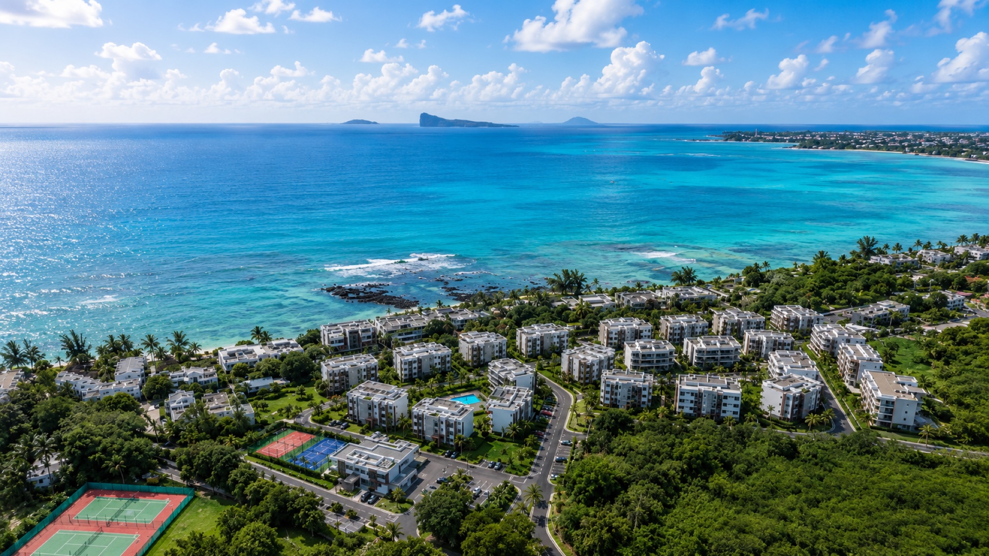 Aerial view of turquoise ocean, islands on the horizon and the La Pointe seafront residence at Pointe aux Canonniers, North Mauritius